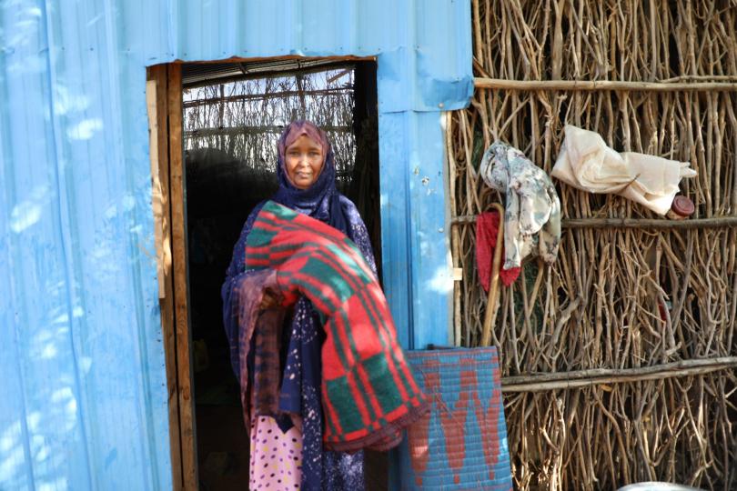 Iadan showing some of the non-food items (NFIs) received while standing in front of her home.