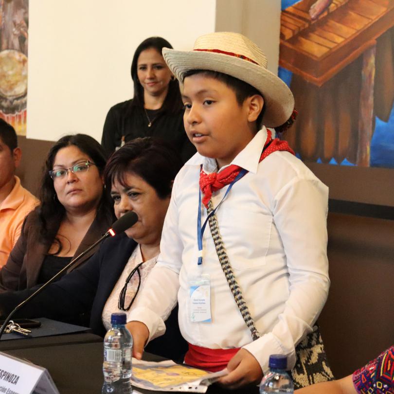 Mayan child wearing a hat, speaking out to national authorities, wearing a traditional costume