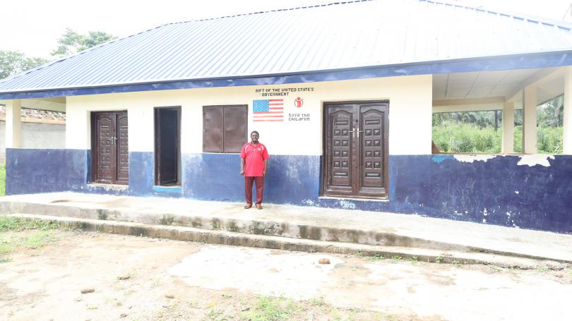 Mr Boniface standing in front of the block built by SCI in his school