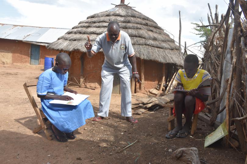 A teacher visits homes to help children learn in a socially distanced way