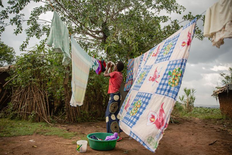 Lydia hangs up her baby's clothes. Esther Mbabazi / Save the Children