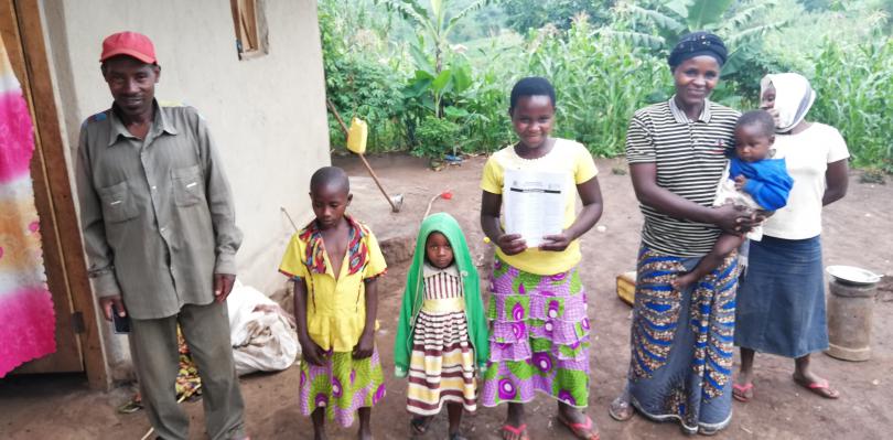 Priscille*, holding learning materials with her family 