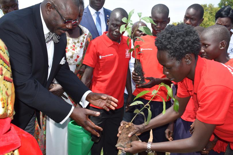 Hon. Oulanya receives a tree seedling to plant. Immaculate Nalubyayi / Save the Children
