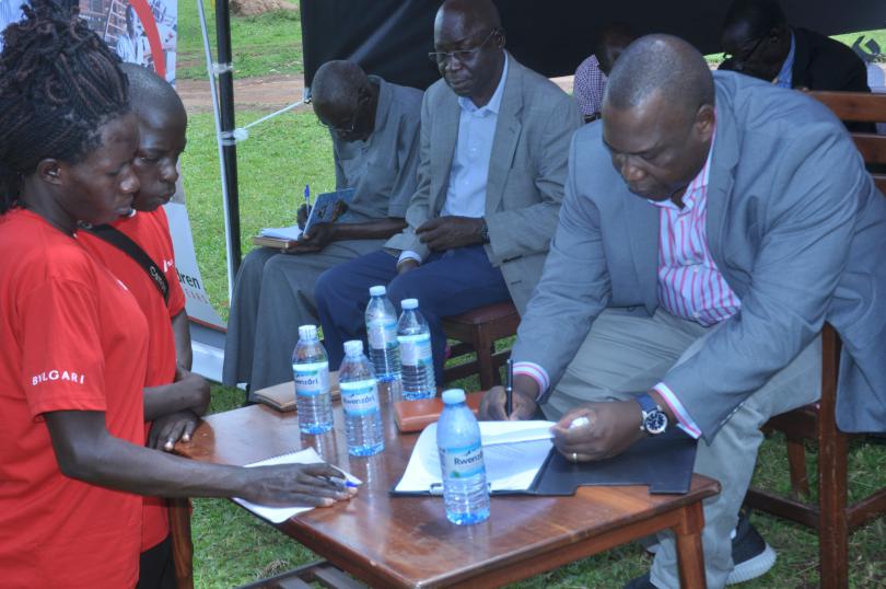 HRH David Onen Acan II signs the youth advocates' petition. Immaculate Nalubyayi / Save the Children