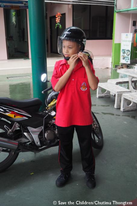 Jean adjusts his helmet chin strap to ensure it fits him well to protect his head before embarking on his motorcycle journey